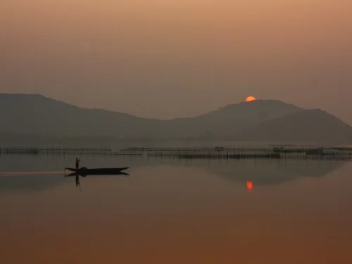 Chilika Lake Odisha fisherman boat sunset silhouette distant hills mountains bamboo fishing nets water reflection serene lagoon, perfect Puri birdwatching dolphin safari tour package.