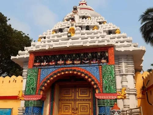 Shree Gundicha Temple entrance at Puri during clear daytime, featuring white spires, colorful deity carvings, ornate arched gate, perfect spiritual experience with Odisha Puri tour package.