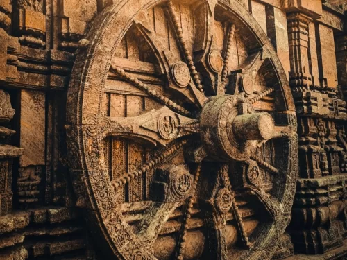 Chariot wheel at Konark Sun Temple Odisha during golden hour, featuring intricate stone carvings, spokes, pillars, perfect heritage experience Odisha tour package. 