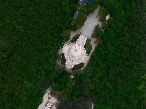 Dhauli Shanti Stupa at Bhubaneswar from aerial view, featuring white dome amid lush greenery, perfect heritage Bhubaneswar tour package.
