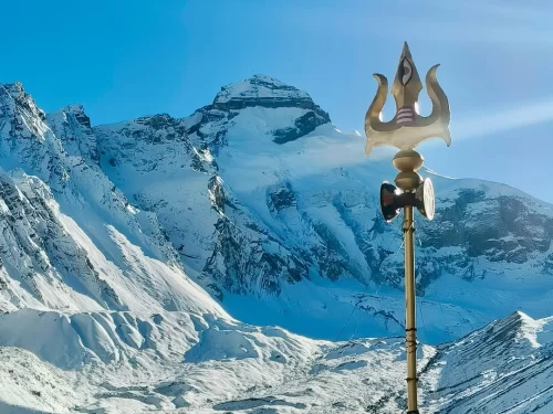 Golden Trishul at Adi Kailash during sunny day, featuring snow-capped peaks and blue sky, perfect spiritual Uttarakhand tour package.