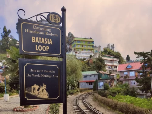 Batasia Loop signboard in Darjeeling during cloudy evening, featuring narrow gauge railway tracks and hillside town, perfect Sikkim tour package