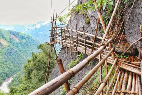 Bamboo Trek in Mawryngkhang, Wahkhen featuring thrilling cliffside bamboo bridges, rugged mountain terrain, and scenic valley views, perfect adventure experience with Meghalaya tour package. 