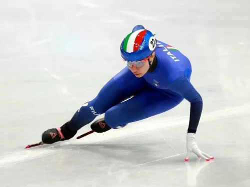 Ice Scating professional athlete speed skating on an indoor ice rink wearing blue racing suit and helmet during competition.