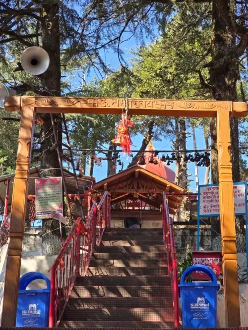 Entrance gate and stairway leading to Mukteshwar Temple surrounded by tall deodar trees in Mukteshwar, Uttarakhand, a peaceful hill destination featured in Uttarakhand tour packages.