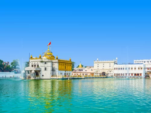 Historic Jallianwala Bagh at Amritsar during sunny day, featuring memorial walls, well, gardens, eternal flame, perfect heritage Amritsar  tour package.