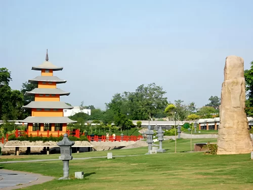 Orange pagoda at Japanese Garden Chandigarh during sunny day, featuring stone lanterns, red bridges, rock pillar, trees, perfect serene Chandigarh tour package.