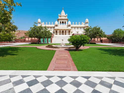 Jaswant Thada courtyard fountain trees lawns checkered marble floor distant dome blue sky backdrop, perfect Rajasthan tour packages. 