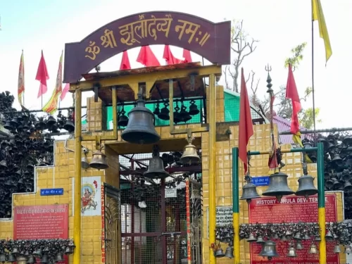 Entrance of Jhula Devi Temple in Ranikhet, Uttarakhand adorned with numerous hanging bells and red flags, a revered shrine included in Uttarakhand tour packages