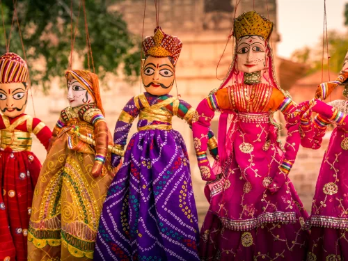 Colorful Rajasthani puppets at Jodhpur's Blue Corridor during sunset, featuring traditional attire and temple backdrop, perfect cultural experience in Rajasthan tour package.