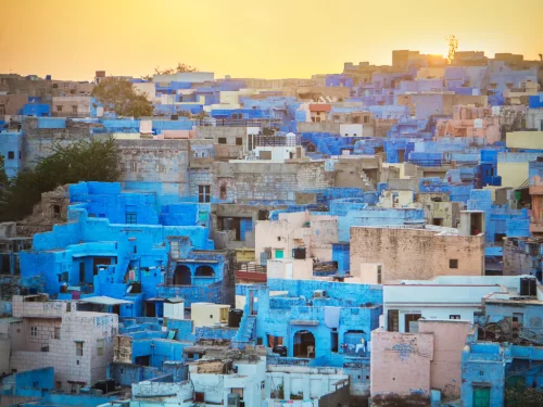 Vibrant blue houses in Jodhpur's Blue City at sunset, featuring clustered rooftops and golden hues, perfect cultural experience in Rajasthan tour package.