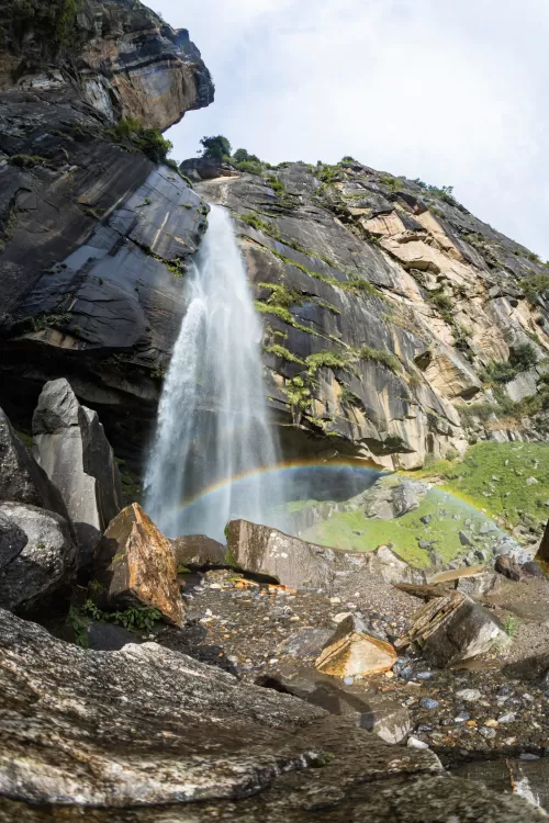 Jogini Waterfall cascading down rocky cliffs with a beautiful rainbow at the base in Manali, Himachal Pradesh, a scenic natural attraction included in Himachal Pradesh tour packages.