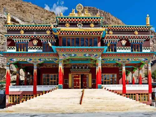 Kalachakra Temple McLeod Ganj Dharamshala Himachal Pradesh, featuring ornate multi-tier Tibetan Buddhist architecture golden roofs colorful murals red doors stairs rocky arid mountain backdrop, perfect cultural experience Himachal tour package.