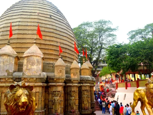 Devotees in queue at Kamakhya Temple Guwahati during soft daylight, featuring shikhara dome, lion statues and red flags, perfect spiritual experience Assam tour package.