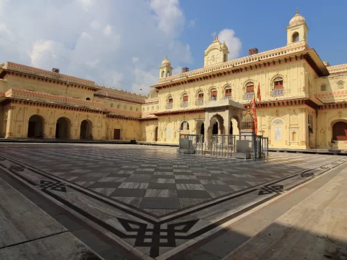 Kanak Bhawan courtyard at Ayodhya during sunny day, featuring ornate arches and flags, perfect cultural experience Uttar Pradesh Tour Packages.