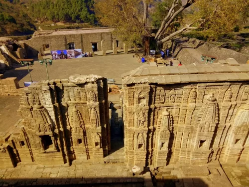 Kangra Fort Kangra near Dharamshala Himachal Pradesh during golden hour autumn lighting, featuring ancient sandstone temple ruins intricate carvings courtyard visitors trees valley backdrop, perfect cultural experience Himachal tour package.