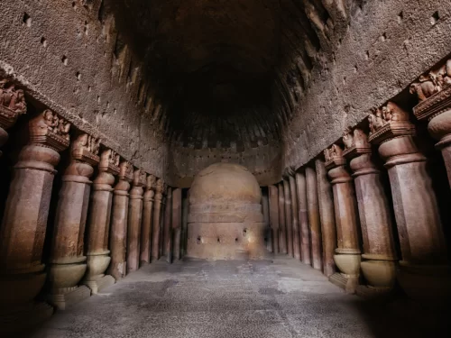 Cave interior at Kanheri Caves Mumbai Maharashtra during dim light, featuring stupa, carved pillars, vaulted ceiling, perfect heritage experience Mumbai tour package.  