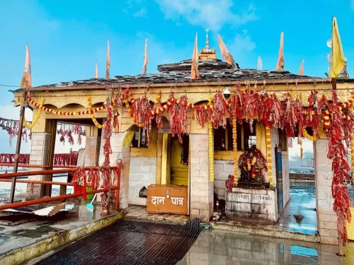 Kartik Swamy Temple in Rudraprayag, Uttarakhand adorned with red prayer flags and garlands, a sacred hilltop shrine included in Uttarakhand tour packages