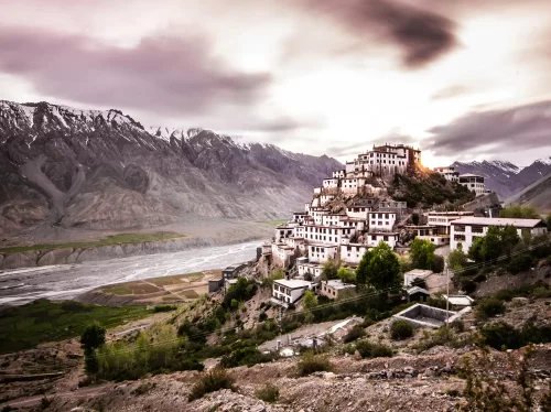 Key Monastery at Losar Spiti during twilight dusk, featuring tiered white monastery rugged mountains river valley, perfect spiritual experience Himachal Pradesh tour package.