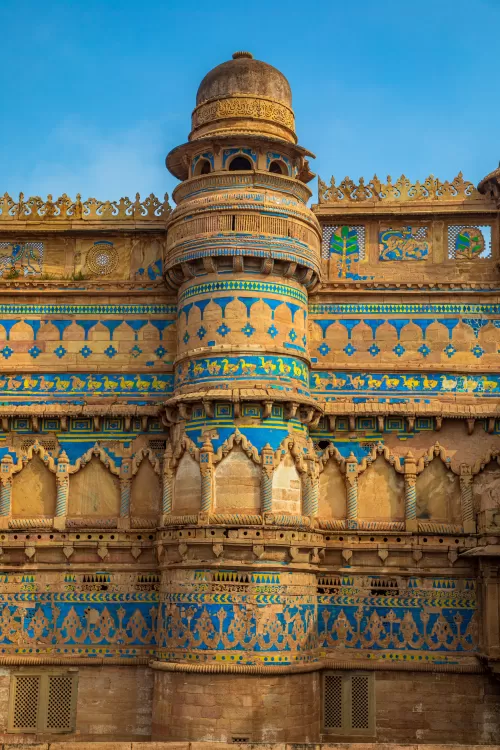 Intricately carved facade of Gwalior Fort showcasing blue tile artwork and historic Rajput architecture highlighting the grandeur of Gwalior heritage tours and Madhya Pradesh travel packages