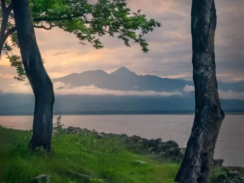 Komlighat Pasighat serene riverside view with misty mountains and sunset hues along the Brahmaputra riverbank in Arunachal Pradesh Package.