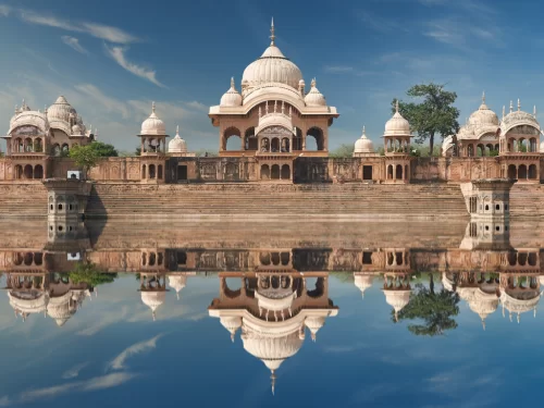 Radha Kund temples at Kusum Sarovar during clear daytime, featuring white domes, pink sandstone pavilions, serene lake reflections, perfect spiritual experience with Mathura Vrindavan tour package. 