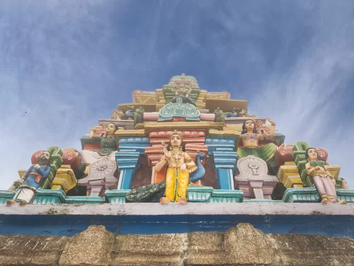 Kuzhanthai Velappar Temple at Poombarai Kodaikanal during sunny day, featuring Lord Murugan idol, colorful gopuram, deities, perfect cultural experience Tamil Nadu tour packages.