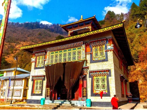 Lachen Monastery Sikkim ornate yellow facade with prayer flags amid autumn hills under blue sky, perfect cultural North Sikkim tour package.