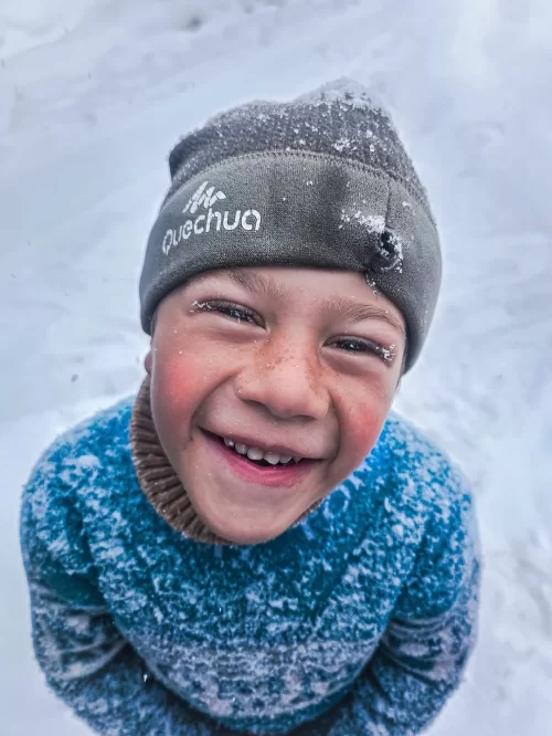Smiling local child in snowy Kargil Ladakh wearing winter clothing, capturing everyday life moments included in Ladakh tour packages