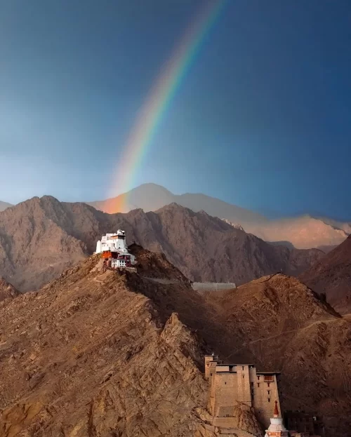 Ladakh monastery on rugged hills with rainbow backdrop featured in Ladakh tour packages