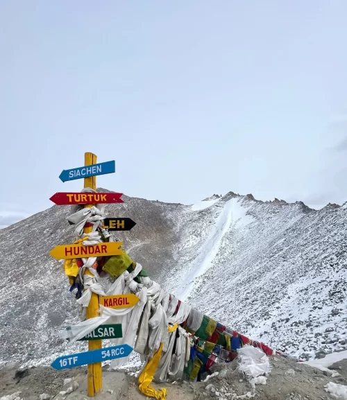 Colorful signpost at snow covered Khardungla Top mountain pass. Ladakh tour packages.