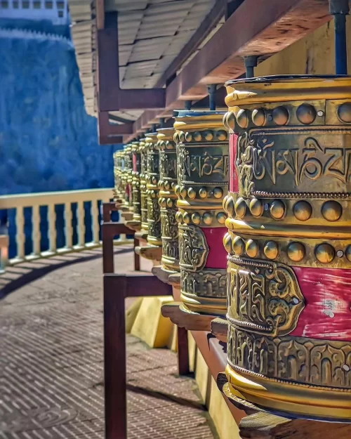 Prayer wheels at Diskit Monastery in Nubra Valley Ladakh with intricate Buddhist carvings, a cultural experience featured in Ladakh tour packages