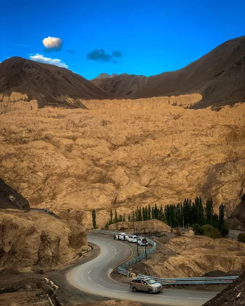 Lamayuru Moonland landscape in Ladakh with winding mountain road and dramatic barren terrain, a scenic highlight of Ladakh tour packages