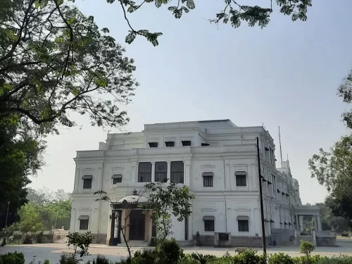 Lal Bagh Palace in Indore, Madhya Pradesh, showcasing its grand white neoclassical architecture surrounded by lush greenery – a heritage highlight included in Madhya Pradesh tour packages.