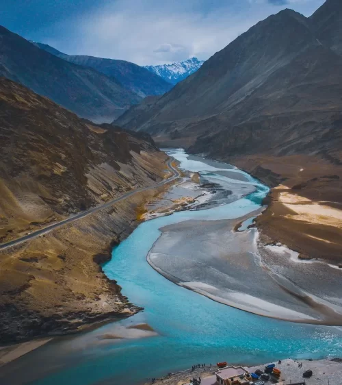 Sangam confluence of Indus and Zanskar rivers in Ladakh with turquoise waters winding through mountain valleys, a scenic highlight in Ladakh tour packages