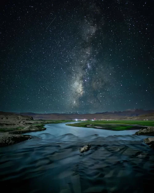Milky Way stretching over Hanle Ladakh with river reflections under a crystal-clear night sky, a mesmerizing highlight in Ladakh tour packages