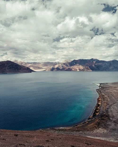 Panoramic view of Tso Moriri Lake in Ladakh with deep blue waters and rugged mountain landscape, a serene highlight in Ladakh tour packages
