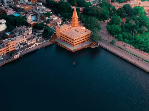  Aerial view of Lower Lake in Bhopal, Madhya Pradesh, with a lakeside temple complex and surrounding cityscape, a scenic urban attraction often included in Madhya Pradesh tour packages