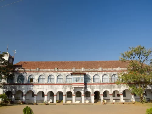 Madikeri Fort at Madikeri Coorg during sunny day, featuring white arched building, red roof, courtyard, trees, perfect cultural experience Karnataka tour packages.