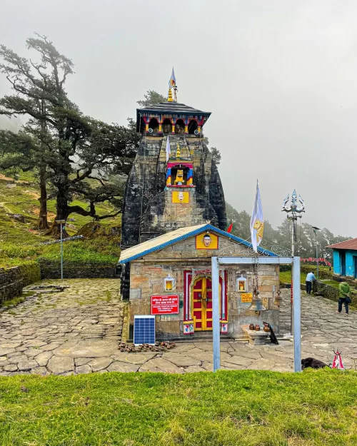 Ancient temple of Panch Kedar in Uttarakhand, adorned with vibrant colors and flags, nestled amidst misty hills—a sacred pilgrimage highlight in Uttarakhand tour packages