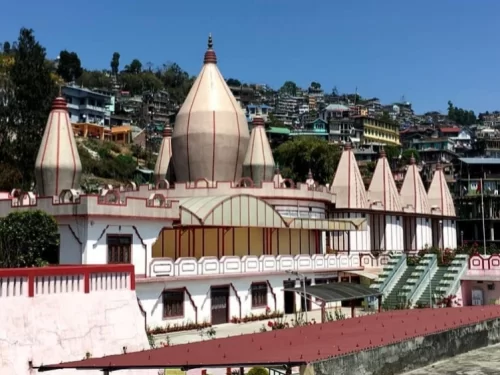 Mangal Dham Temple in Kalimpong, West Bengal, featuring distinctive white and red temple domes set against hillside homes, a revered religious site included in West Bengal tour packages.