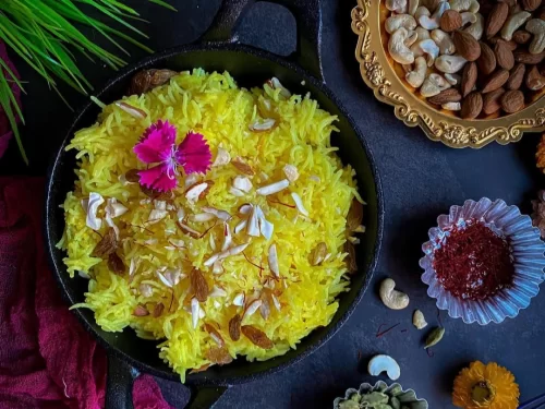 Meetha Bhat, a fragrant Kashmiri-style sweet rice cooked with saffron, ghee, and sugar, garnished with nuts and dried fruits.