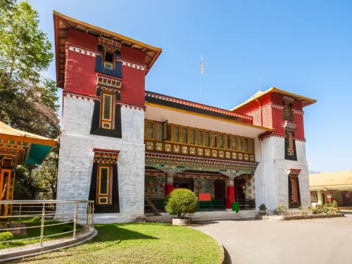 Namgyal Institute of Tibetology Gangtok during sunny day, featuring traditional Tibetan architecture red towers manicured lawn, perfect cultural heritage experience Sikkim tour package. ​