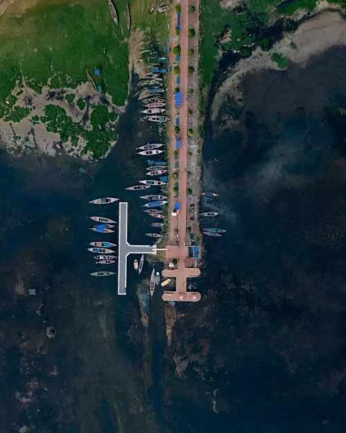 Aerial view of boats docked at jetty in Chilika Lake Odisha surrounded by blue waters and green landscape ideal for Odisha tour packages