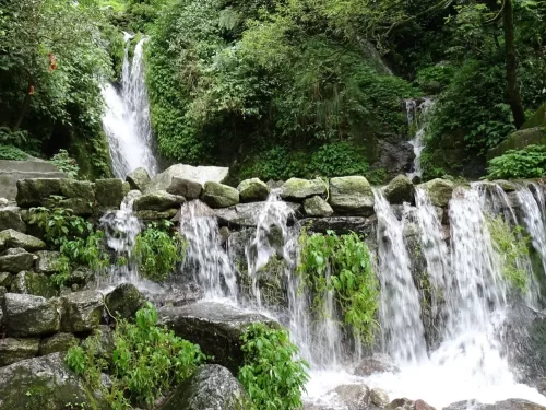 Cascading Panchpula waterfall at Dalhousie during misty monsoon, featuring lush green forests, rocky cascade, perfect adventure Himachal Pradesh tour package.