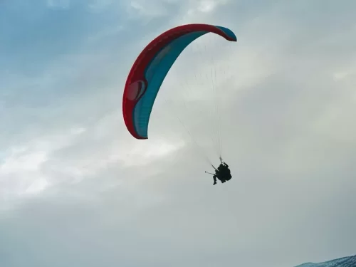 Paragliding adventure with a pilot soaring high under a colorful parachute canopy against the open sky.