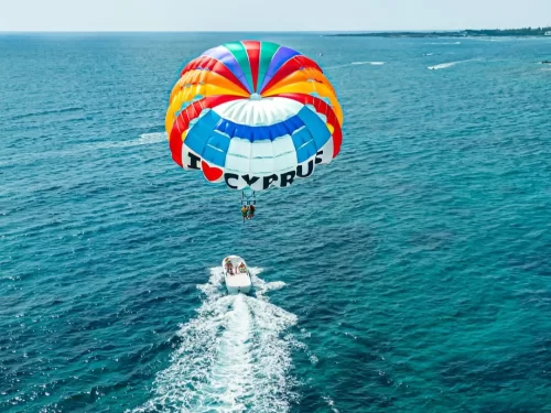Parasailing adventure with colorful parachute soaring above the ocean pulled by a speedboat.