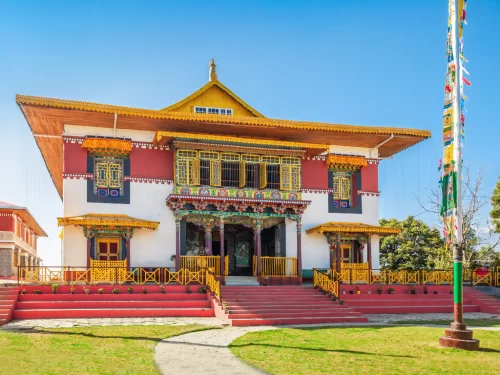 Pemayangtse Monastery during clear daylight, featuring ornate Tibetan architecture and prayer flags, perfect spiritual Sikkim tour package.