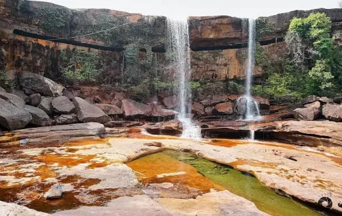 Phe Phe Falls in Meghalaya, a scenic twin-stream waterfall cascading over rocky cliffs into natural pools surrounded by rugged landscapes.