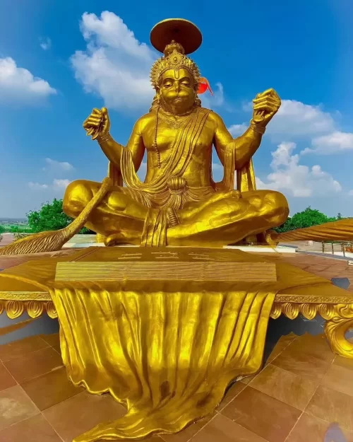 72-ft golden Hanuman statue at Pitra Parvat Indore during clear daylight, featuring meditative pose saffron flag, perfect spiritual Madhya Pradesh tour package.